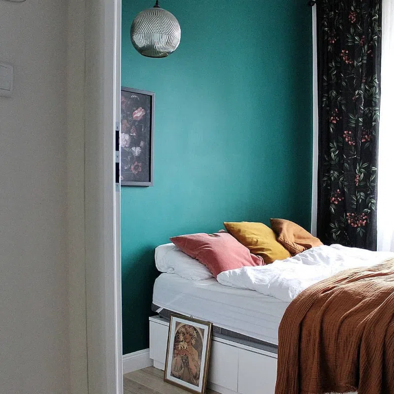 Зеленая стена M371 с песочными и розовыми подушками в спальне