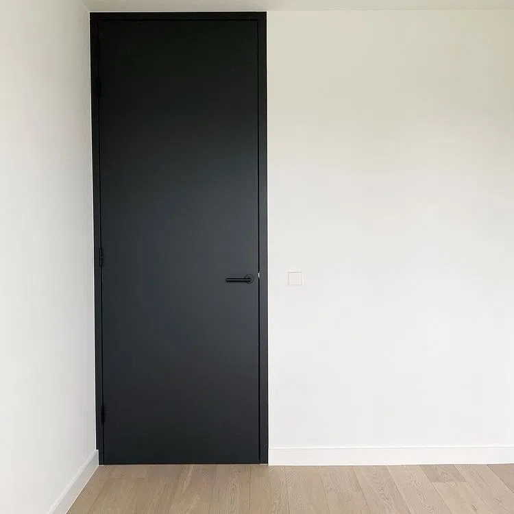 Интерьер в стиле минимализм. Высокая черная дверь с белыми стенами RAL9016